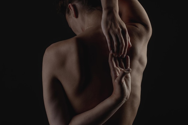 Gros plan du dos de la fille sur un fond sombre le concept de traitement de la colonne vertébrale et du dos
