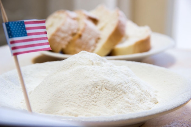 Gros plan du drapeau américain et de la farine dans une assiette Tranches de pain sur le fond