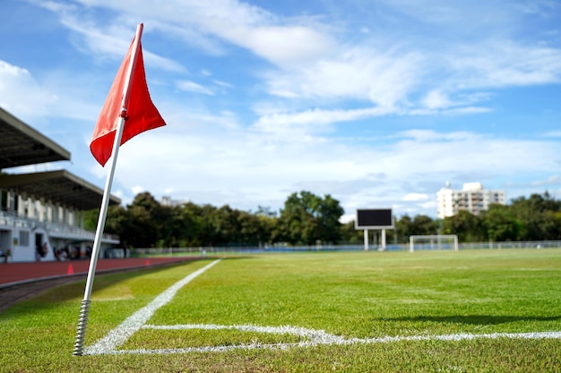 Gros plan du drapeau rouge dans un coin de terrain de football avec un ciel bleu vif