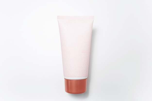 Gros plan du flacon de tube de crème avec blanc de couleur rose sur fond blanc