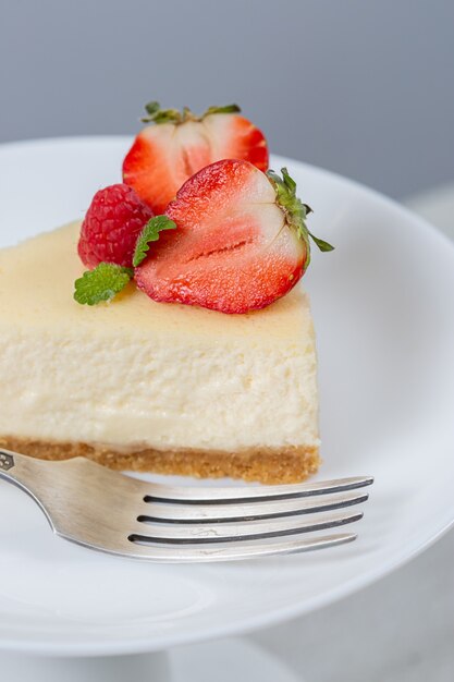 Gros plan du gâteau au fromage aux fraises sur une plaque blanche sur un stand de gâteau