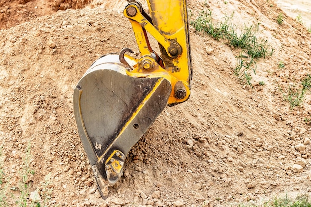 Photo gros plan du godet de l'excavatrice sur le chantier de construction matériel de construction pour les travaux de terrassement