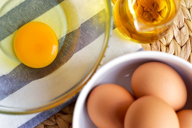 Gros plan du jaune d&#39;oeuf dans un bol en verre transparent sur un chiffon bleu et blanc avec des oeufs de poule