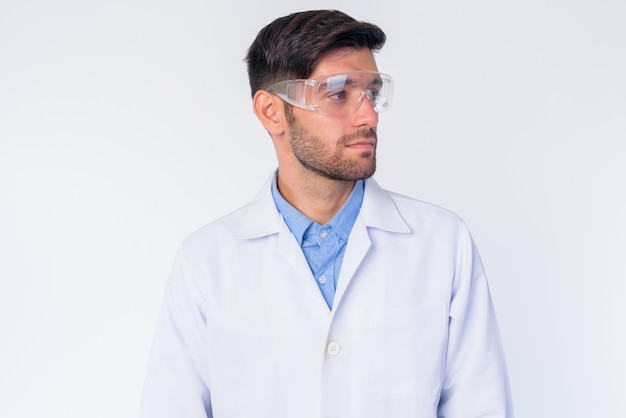 Gros plan du jeune beau médecin persan barbu avec des lunettes de protection isolées