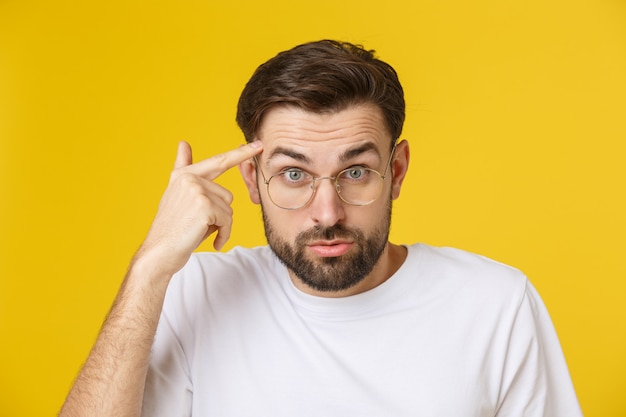 Gros plan du jeune bel homme à la recherche et montrant la grimace à la caméra, portant du verre.