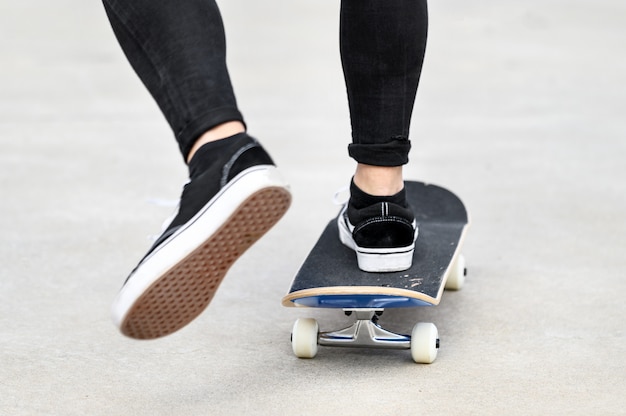 Gros plan du jeune homme monté sur une planche à roulettes au skate park.