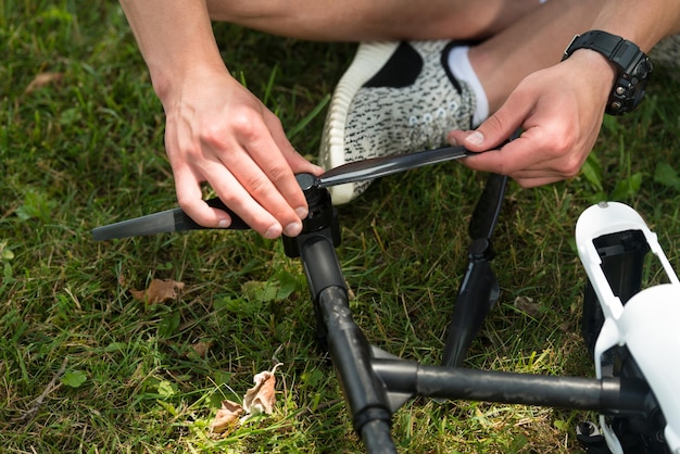 Gros plan du jeune ingénieur serrant l'hélice du drone Uav avec outil à main dans le parc