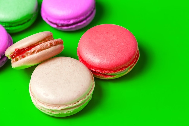 Gros plan du macaron rose et violet coloré sur fond vert. Pâtisseries sucrées, Petit déjeuner