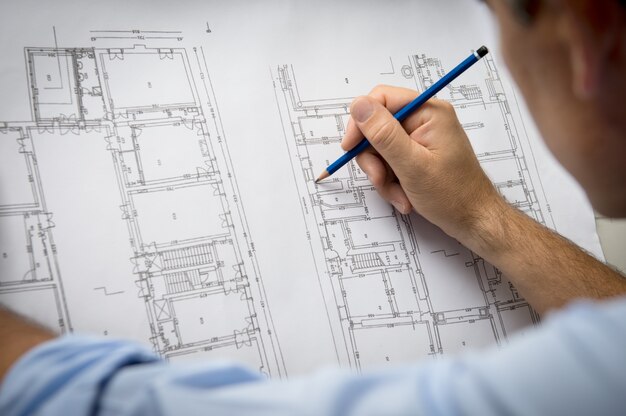 Gros plan du mâle architecte travaillant sur le plan au bureau