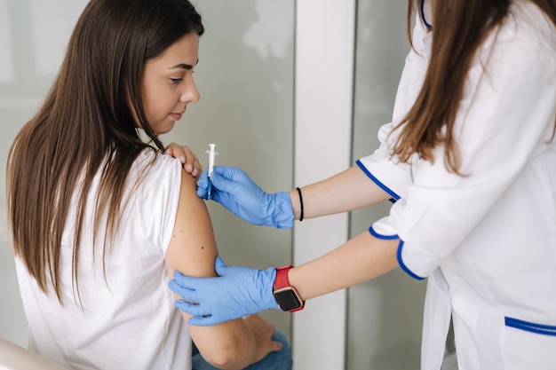 Gros plan du médecin dans des gants de protection tenant une seringue et utilisant du coton avant de faire l'injection à