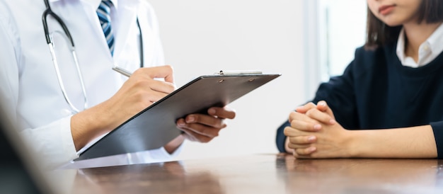 Gros plan du médecin et du patient assis les mains à la table et parlant de l&#39;état du patient.