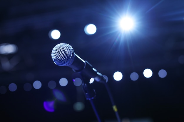 Gros plan du microphone dans la salle de concert ou la salle de conférence avec des lumières froides en arrière-plan.