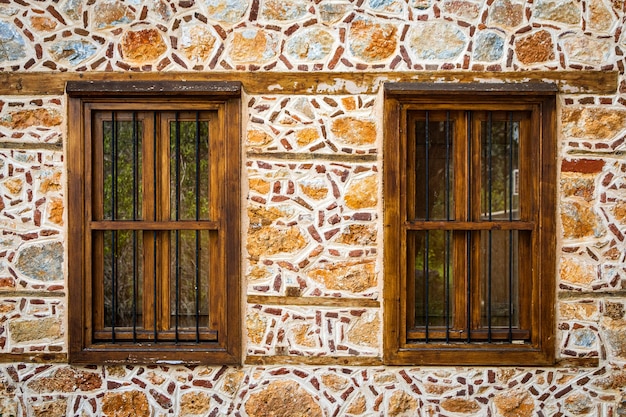Gros plan du mur d'une maison en pierre avec fenêtres et volets en bois. Ancienne architecture européenne