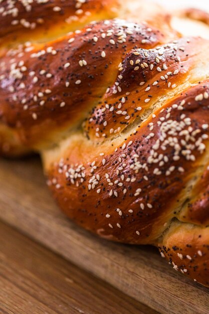 Gros plan sur du pain challah tressé avec des graines de sésame et de pavot.