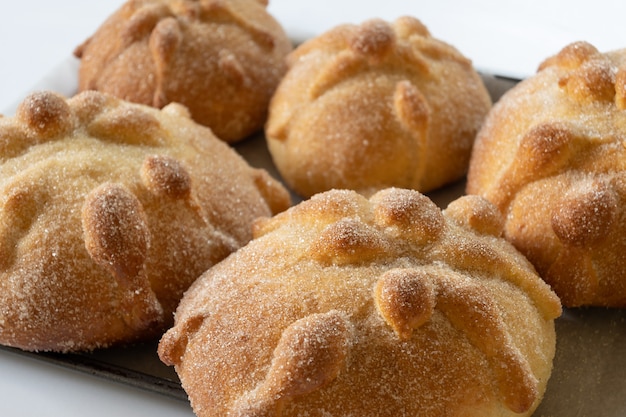 Gros plan du pan de muerto mexicain traditionnel avec du sucre et de la cannelle sur fond blanc, focus select, concept dia de muertos