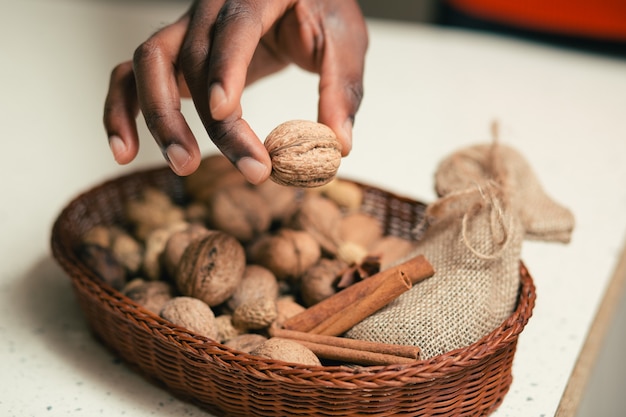 Gros plan du panier en osier avec des noix et des écorces de cannelle. Main avec noyer sur le panier