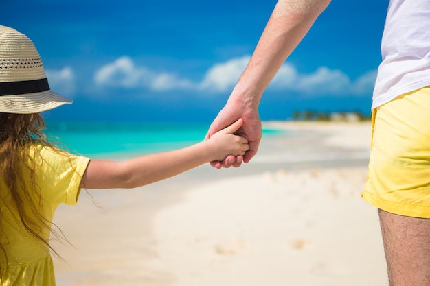 Gros plan du père et de la petite fille se tenant par la main à la plage