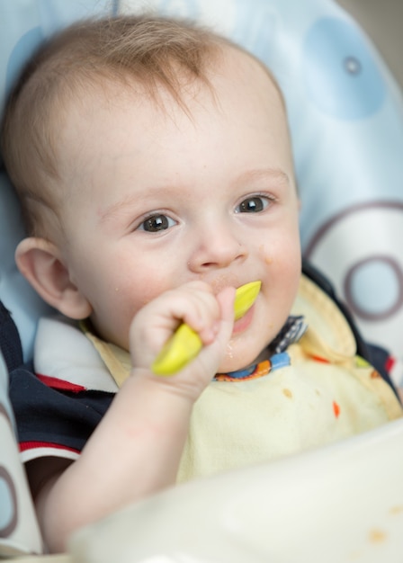 Gros plan du petit garçon souriant mangeant de la bouillie de cuillère