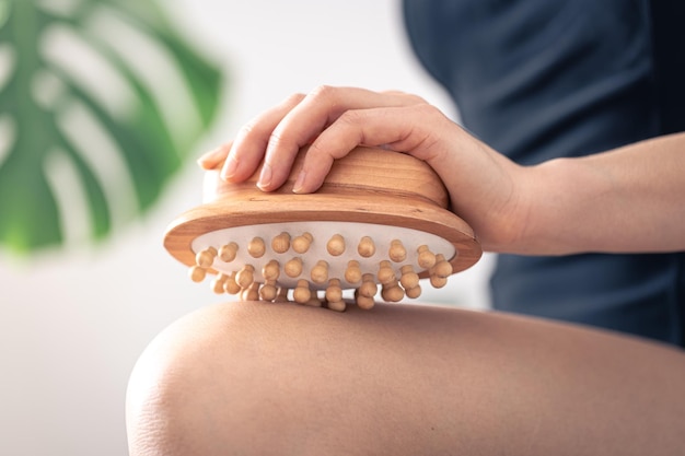 Gros plan du pinceau de massage anticellulite dans les mains des femmes