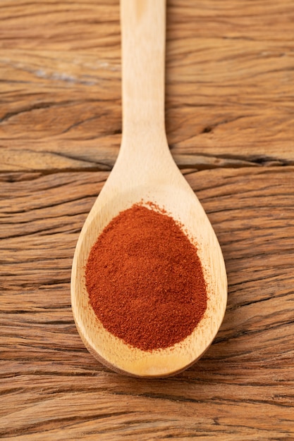 Gros plan du poivre de paprika rouge sur une cuillère sur une table en bois.