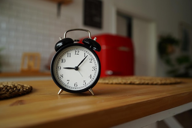 Gros plan du réveil sur la table dans la cuisine Horloge vintage noire sur la table de la cuisine