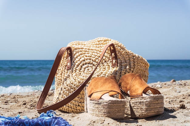 Gros plan du sac à main des femmes et des chaussures sur la plage