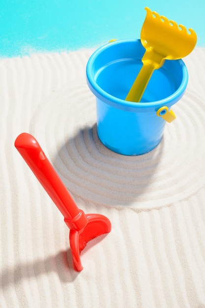 Photo gros plan du seau bleu avec pelle et râteau sur le sable