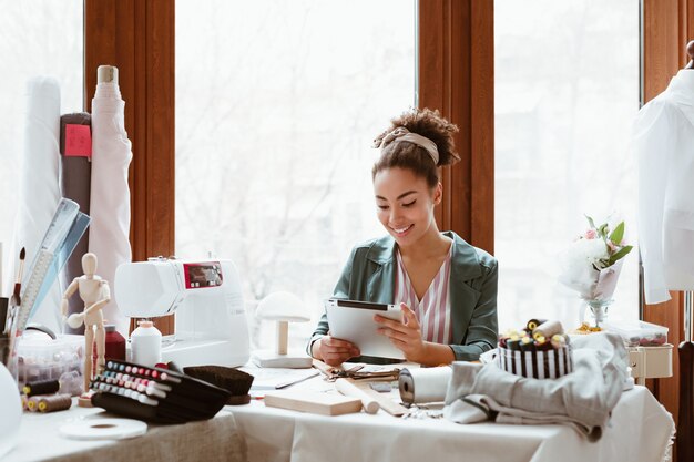 Le gros plan du tailleur de la jeune femme avec la tablette numérique modélise de nouveaux vêtements