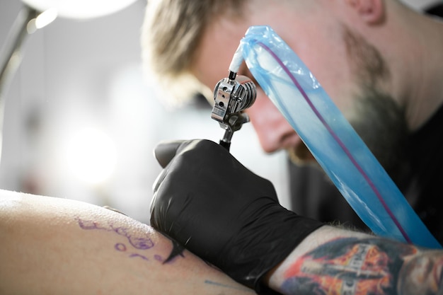 Le gros plan du tatoueur s'appuie sur la hanche de la fille