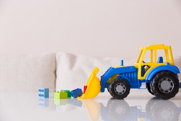 Gros plan du tracteur jouet pour enfants avec des briques en plastique colorées ou des détails sur fond blanc