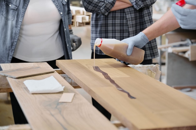 Gros plan du travailleur main dans des gants de protection avec finition housse de protection pour le bois