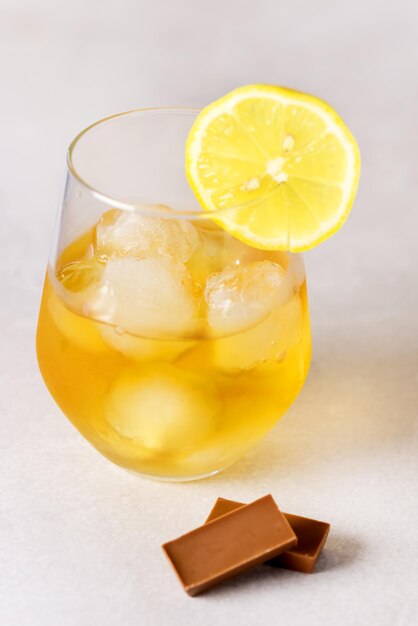 Gros plan du verre avec une boisson forte et des collations telles que le citron et le chocolat vertical