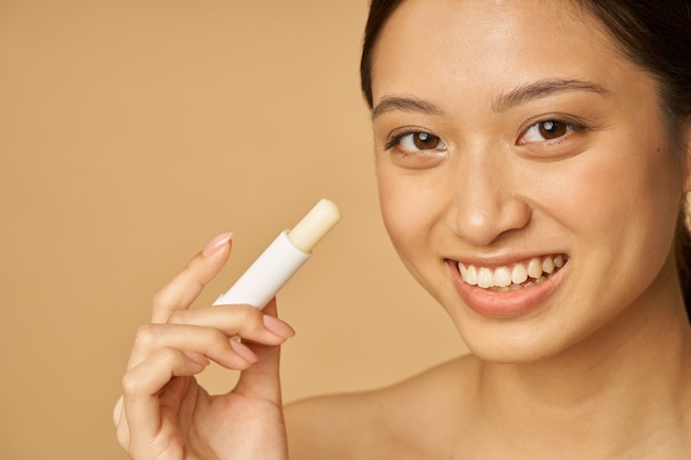 Gros plan du visage d'une adorable jeune femme avec un beau sourire regardant la caméra et tenant la lèvre