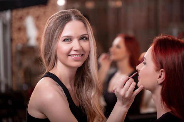 Gros plan du visage de la belle jeune femme avec le maquillage de beauté peau douce douce et longs cils épais noirs appliquant le mascara avec la brosse cosmétique Concept de maquillage et de cosmétiques haute résolution