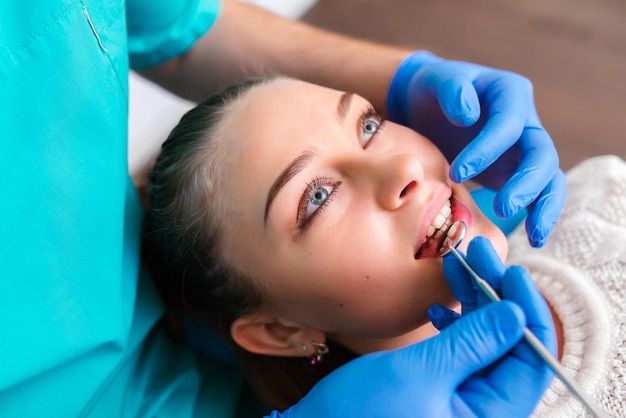 Gros plan du visage d'une jeune belle fille montrant des dents avec des accolades métalliques et regardant la caméra Patiente dans une clinique dentaire Alignement des dents mettant des accolades