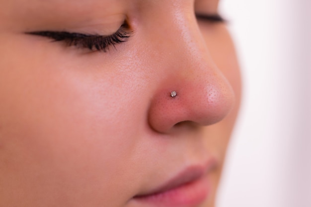 Gros plan du visage d'une jeune femme avec piercing suspendu à son nez