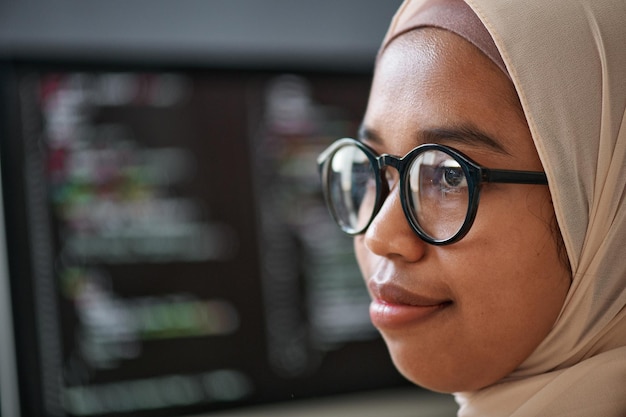 Gros plan du visage d'un jeune stagiaire musulman confiant en hijab et lunettes debout devant la caméra