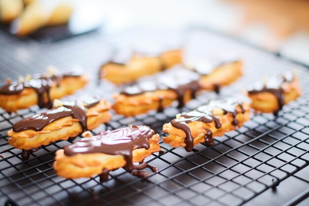 Gros plan d'éclairs avec glaçage au chocolat brillant sur une grille de refroidissement