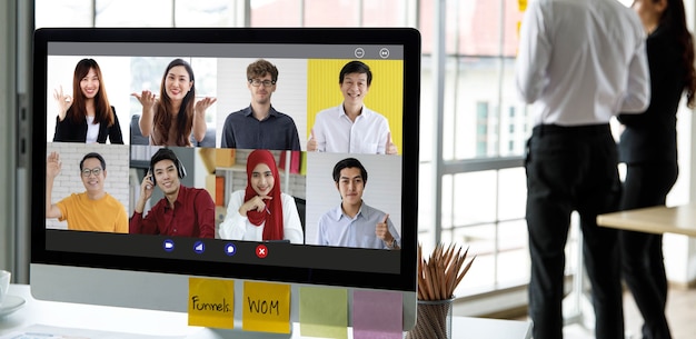 Gros plan sur un écran d'ordinateur montrant un collègue et un client lors d'une réunion de téléconférence vidéo multiculturelle mondiale au bureau de l'entreprise. Le personnel non identifié et méconnaissable fait une pause.