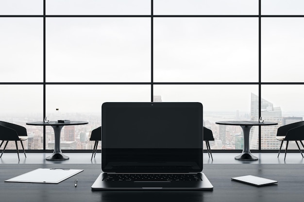 Gros plan sur un écran d'ordinateur portable vide sur un bureau gris avec des fournitures sur une fenêtre panoramique et un fond de vue sur la ville Maquette de rendu 3D