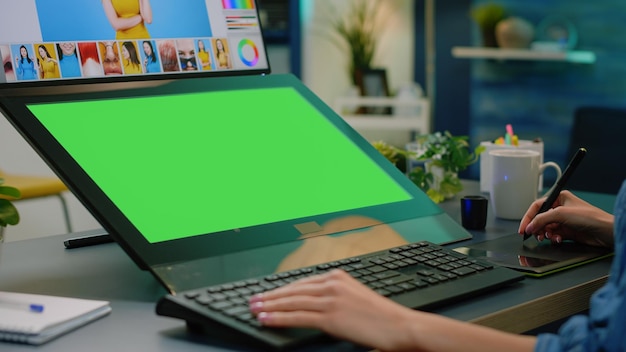 Gros plan sur un écran vert horizontal sur ordinateur avec application de retouche. Photographe éditant des photos avec une tablette graphique tout en ayant une clé chroma avec un modèle de maquette et un arrière-plan isolé