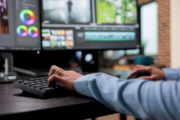 Photo gros plan d'un éditeur vidéo numérique assis au bureau d'un poste de travail multi-écrans tout en travaillant sur des séquences vidéo. vidéaste de maison de post-production créative améliorant la qualité visuelle des cadres de film.