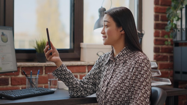 Gros plan sur un employé utilisant un appel vidéo sur un smartphone pour parler à un collègue d'un projet d'entreprise. Employé de l'entreprise parlant par vidéoconférence à distance en ligne, tenant un téléphone portable pour discuter.