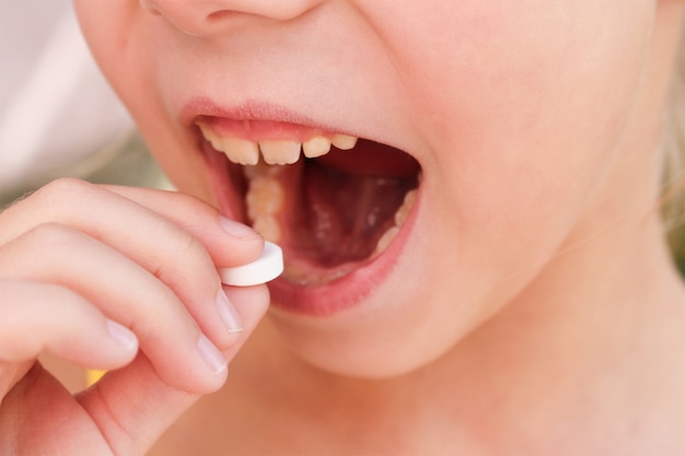 Gros plan de l'enfant met la pilule dans sa bouche