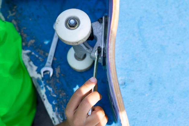 Gros plan d'un enfant réparant la roue de son skateboard après l'avoir utilisé dans le parc des skateurs