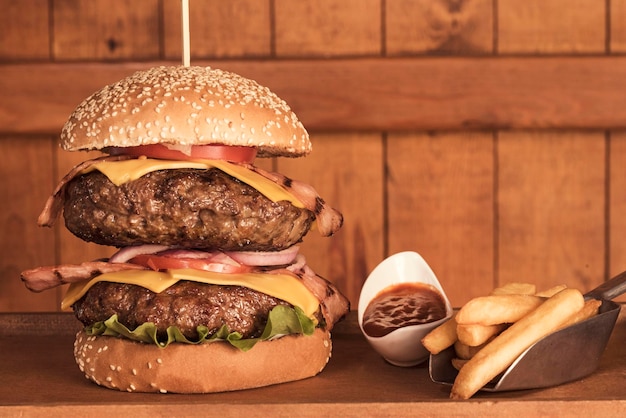 Un gros plan d'un énorme double bacon et un cheeseburger et des frites
