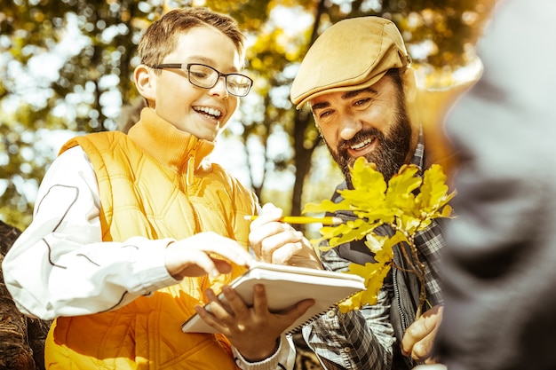 Gros plan d'un enseignant et petit élève dans la forêt d'automne ayant une leçon d'écologie sur une bonne journée