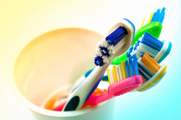 Gros plan d'un ensemble de brosses à dents multicolores en verre sur des toilettes propres sur blanc, concept dentaire.