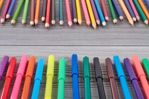 Gros plan sur un ensemble de stylos colorés sur des feutres et des crayons de bureau gris