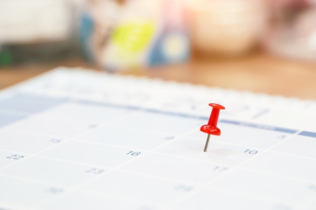 Photo gros plan sur une épingle rouge sur un calendrier de bureau vierge.